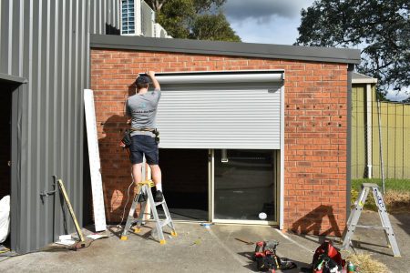 Roller blinds being installed over a sliding door by east blinds